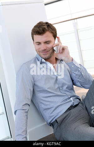 Uomo bello avente phonecall al lavoro Foto Stock