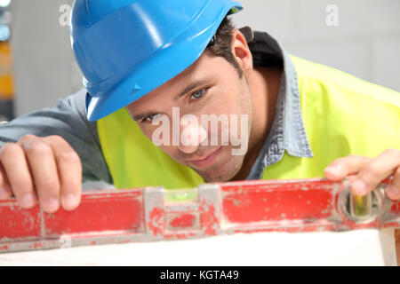 Lavoratore utilizza il livello sul sito di costruzione Foto Stock