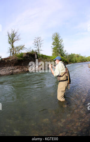 Pescatore con la lenza da pesca in fiume Foto Stock