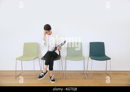 Donna seduta su una sedia in attesa per il colloquio di lavoro Foto Stock