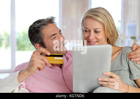 Giovane seduto in poltrona a casa e di fare shopping on line Foto Stock