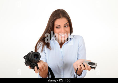 Giovane donna confrontando compatte digitali e delle fotocamere reflex Foto Stock