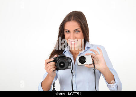 Giovane donna confrontando compatte digitali e delle fotocamere reflex Foto Stock