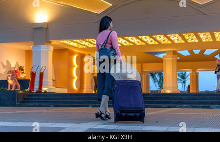 Giovane donna con trolley bag entrando nella lobby dell'hotel. Foto Stock