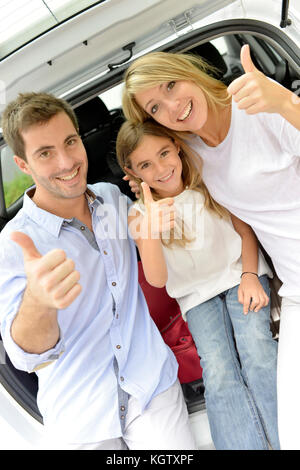 Famiglia allegra nel baule auto mostra pollice in alto Foto Stock