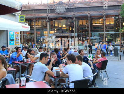 La gente seduta a street cafe vicino Mercado de San Miguel mercato, il centro cittadino di Madrid, Spagna Foto Stock