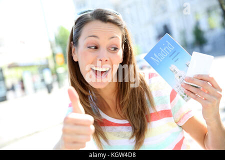 Ragazza allegra a madrid tenendo la guida della città e tousist pass Foto Stock