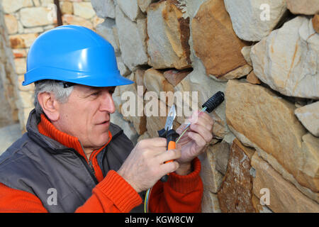 Lavoratore con casco di sicurezza installazione sistema di gate Foto Stock