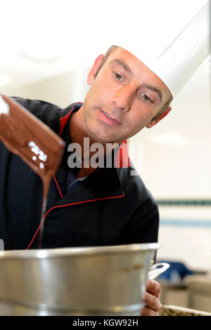 Chef in pasticceria guardando la torta al cioccolato la miscelazione Foto Stock