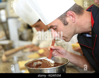 Chef in pasticceria guardando la torta al cioccolato la miscelazione Foto Stock