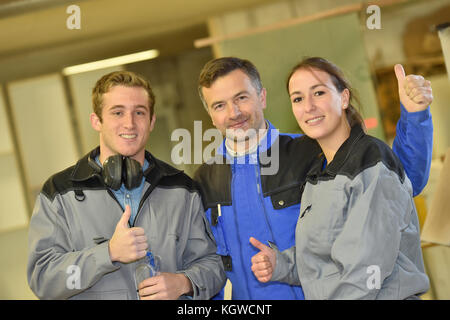 Allegro trainer con gli studenti in laboratorio che mostra pollice in alto Foto Stock