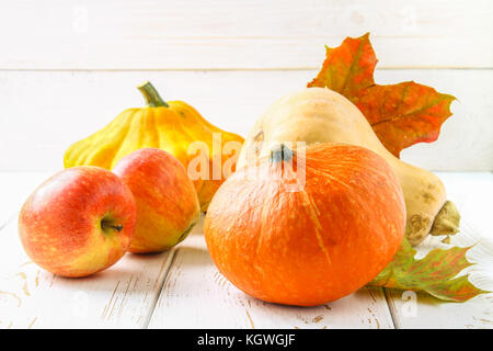 Zucca e Patty pan, mele e acero, rovere foglie gialle su una bianca tavolo in legno. raccolto autunnale Foto Stock