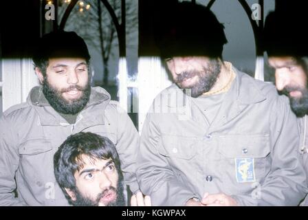 Scena di quattro uomini barbuti che indossano uniformi militari impegnati in una discussione, in un hotel in Iran, marzo 1983. Danni estesi alla foto originale. () Foto Stock