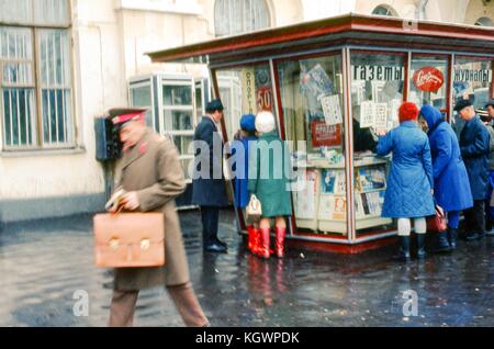 Scena su una strada di Mosca di persone fodera fino al di fuori di un chiosco edicola, novembre 1973. i segni in russo pubblicizzare la vendita di quotidiani e riviste. in primo piano, un uomo in uniforme passeggiate con valigetta in mano. () Foto Stock