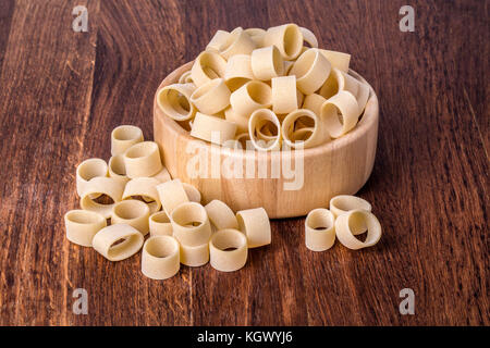 Paste alimentari non cotte calamarata in vaso su sfondo di legno Foto Stock