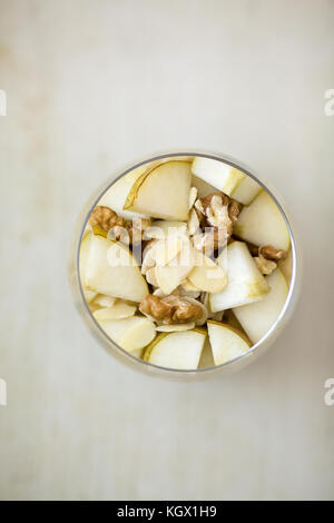 Farina di avena crema di farina e di latte aromatizzato con purea di banana, guarnita con fette di pera, noci, mandorle e miele, vista da sopra, servita in un chiaro vetro rotondo, pl Foto Stock