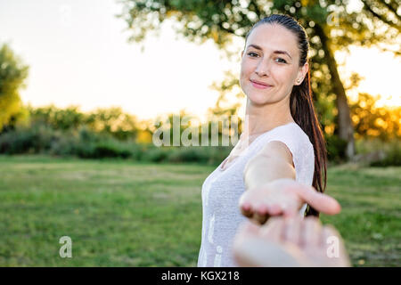 Bellissima giovane donna caucasica raggiungendo verso la telecamera con la mano sinistra Foto Stock