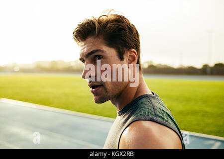 Primo piano di un velocista in piedi su una via di corsa. Runner guardando lontano in piedi sulla via. Foto Stock