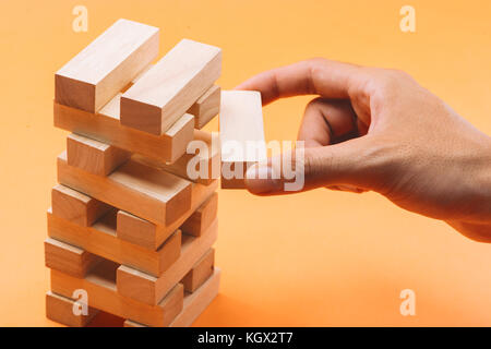 Imprenditore il gioco d'azzardo posizionando il blocco di legno su una torre Foto Stock