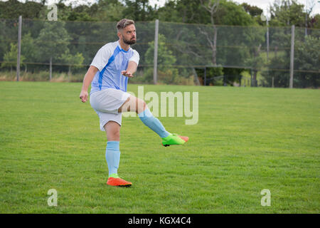 Giocatore di calcio giocando a calcio nel terreno Foto Stock