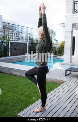 La donna a praticare yoga nel portico in una giornata di sole Foto Stock