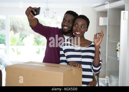 Coppia felice che mostra chiave di casa tenendo selfie con telefono mobile Foto Stock