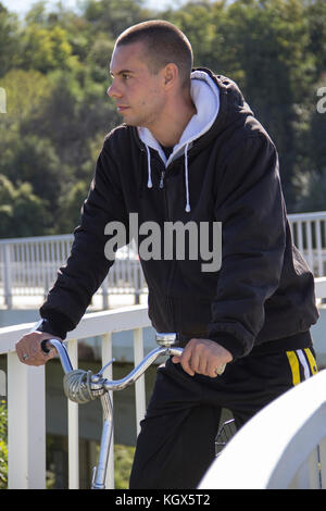 Un giovane uomo, gopnik, seduto su una bicicletta Foto Stock