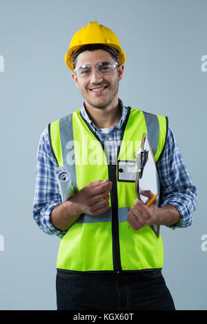 Ritratto di sorridente architetto maschio holding negli appunti e blueprint contro uno sfondo bianco Foto Stock
