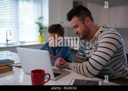 Padre ad assistere la figlia in i suoi studi a tavola Foto Stock