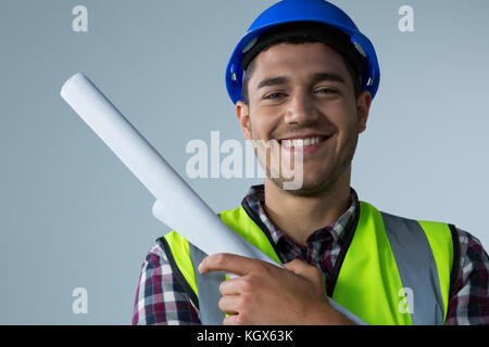 Ritratto di sorridente architetto maschio blueprint di contenimento contro uno sfondo bianco Foto Stock