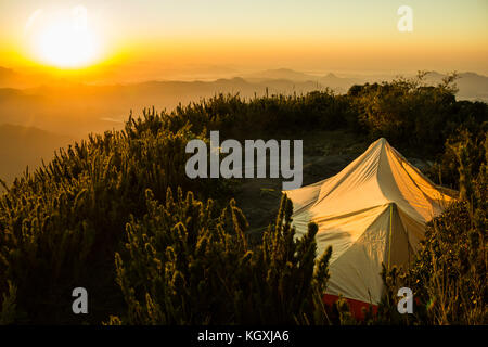 Luce dorata di colpire una tenda bianca sulla cima di una montagna Foto Stock