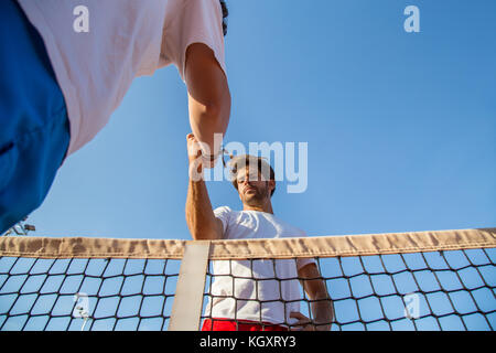 Due tennisti professionisti tenendo le mani sul tennis net prima partita. Foto Stock