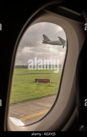 British Airways piano arrivando in terra come osservata attraverso una finestra di piano sulla pista di rullaggio mentre si è in attesa di discostarsi dall'aeroporto di Dublino, Irlanda Foto Stock