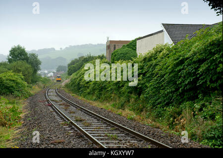 Rob Waistell chi è bungalow (edificio color crema) in Maesteg, Wales, Regno Unito, è disturbata dalla knotweed giapponese che ha diffuso lungo la linea ferroviaria. Foto Stock