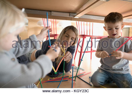 La madre e il bambino bambini che giocano con i bastoni del connettore sotto la tabella