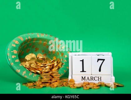 I blocchi di legno che mostra la data di calendario marzo 17th, san patrizio, seduti su sfondo verde, leprechaun hat con monete d oro riversandosi accanto a bl Foto Stock