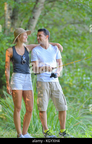 Coppia giovane la pesca sulla riva del fiume in erba Foto Stock