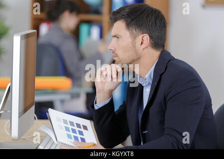 L'uomo facendo alcuni lavori di progettazione in un computer desktop Foto Stock