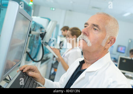 Senior farmacista maschio in un laboratorio di bianco il controllo dei risultati Foto Stock