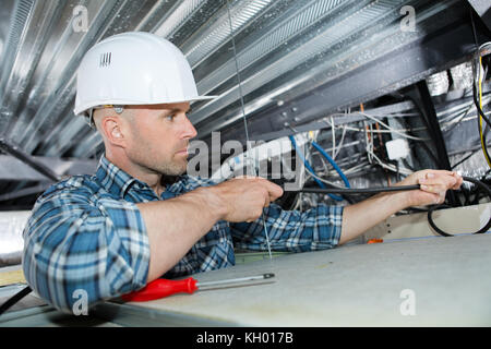 Elettricista maschio su scala installazione di luce sul soffitto Foto Stock
