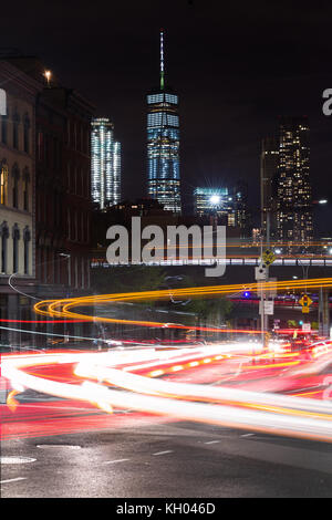 Luci del veicolo una lunga esposizione su occupato Brooklyn Bridge Road con One World Trade Center e grattacieli di Manhattan in background, New York, Stati Uniti d'America Foto Stock