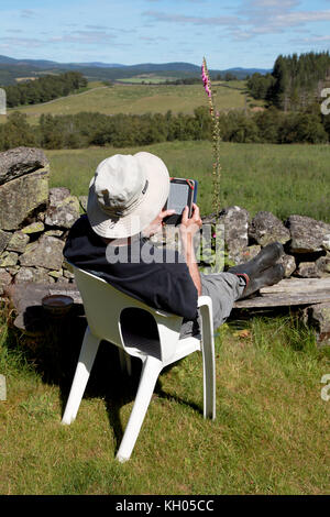 Un uomo in pensione il relax in vacanza e la lettura di un libro su un Amazon Kindle Foto Stock