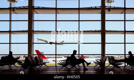 Silhouette la gente in un aeroporto e aerei a sembrare dalla finestra. Foto Stock