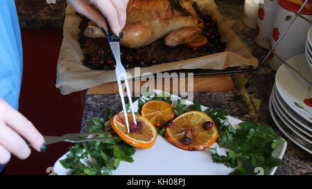 Mani femminili decorano arrostito intero pollo sulla piastra per la cena in famiglia. Foto Stock