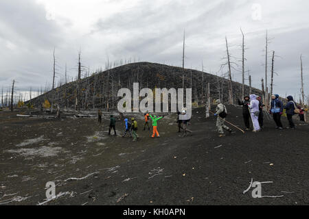 Penisola di Kamchatka, Vulcano Tolbachik: Un gruppo di turisti cammina nel bosco morto - conseguenza di un disastro naturale - vulcano eruzioni catastrofiche. Foto Stock