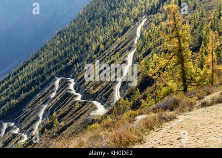 La pittoresca vista superiore sull'avvolgimento ripida strada di ghiaia attraverso il pass, parte della serpentina di montagna, passando il pendio della montagna Foto Stock