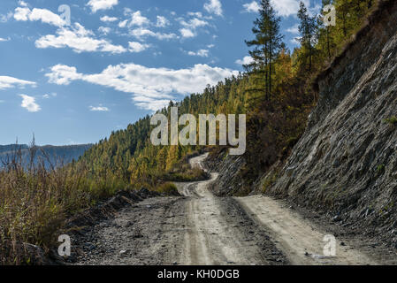 La pittoresca vista sull'avvolgimento ripida strada di ghiaia attraverso il pass, parte della serpentina di montagna, passando il pendio della montagna Foto Stock