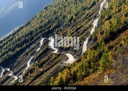 La pittoresca vista superiore sull'avvolgimento ripida strada di ghiaia attraverso il pass, parte della serpentina di montagna, passando il pendio della montagna Foto Stock