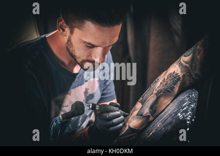 Professional tattoo artist fa un tatuaggio su una giovane mano d'uomo Foto Stock