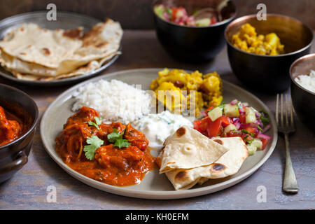 Pasto indiano con tikka masala di pollo, aloo gobi, raita, focaccine e insalata Foto Stock